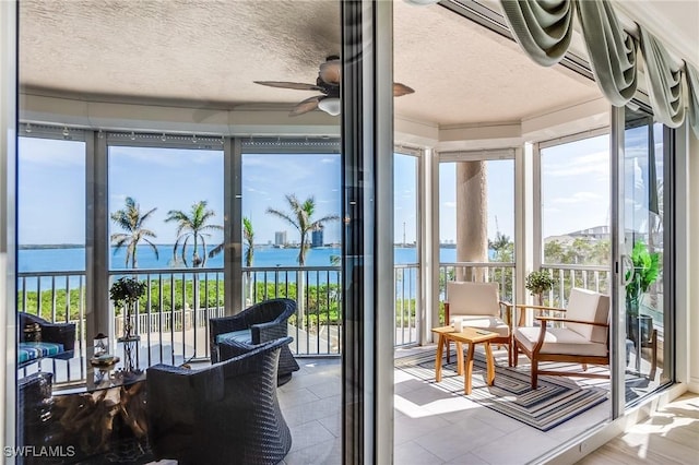 sunroom / solarium featuring ceiling fan and a water view