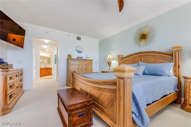 bedroom featuring ensuite bathroom, crown molding, and light carpet