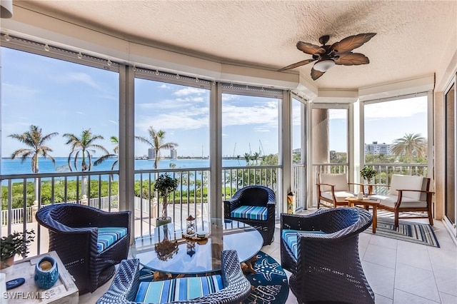 sunroom / solarium featuring ceiling fan and a water view