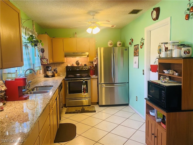 kitchen featuring stainless steel appliances, sink, light stone counters, a textured ceiling, and tasteful backsplash