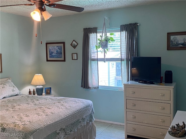 bedroom featuring ceiling fan, light tile patterned flooring, a textured ceiling, and multiple windows