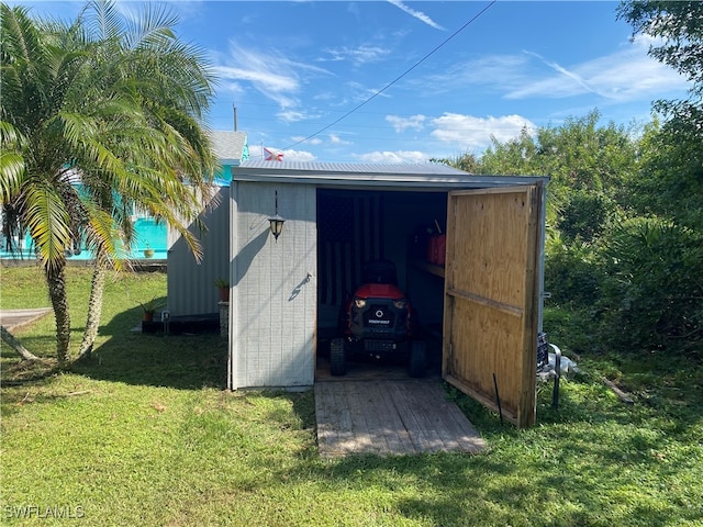 view of outdoor structure with a carport and a lawn