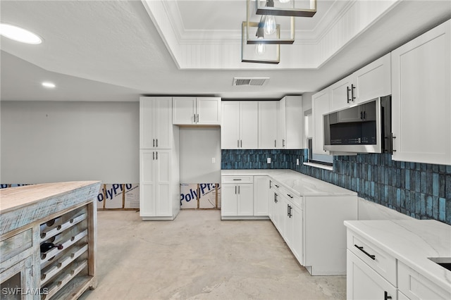 kitchen with ornamental molding, white cabinetry, light stone counters, and backsplash