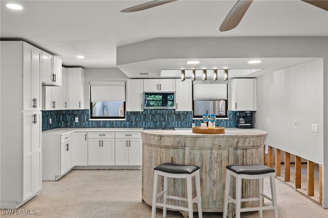 435 Donora Blvd, Fort Myers Beach, FL 33931 - kitchen with decorative backsplash, ceiling fan, a center island, stainless steel microwave, and white cabinets