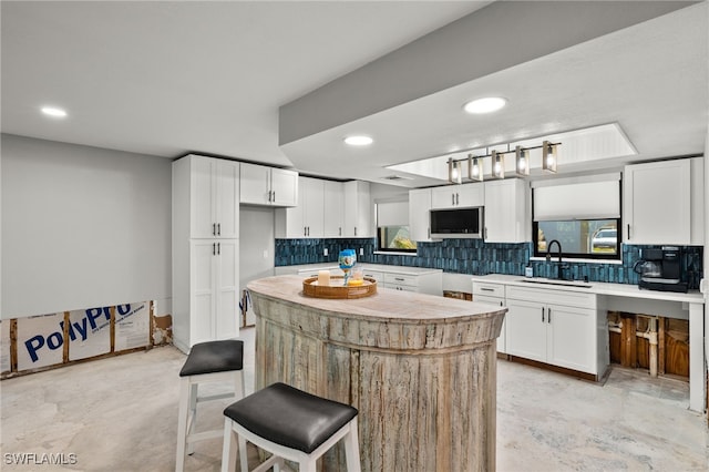 435 Donora Blvd, Fort Myers Beach, FL 33931 - kitchen with a sink, white cabinetry, decorative backsplash, a kitchen bar, and a kitchen island