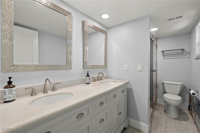 bathroom with toilet, hardwood / wood-style floors, walk in shower, and vanity