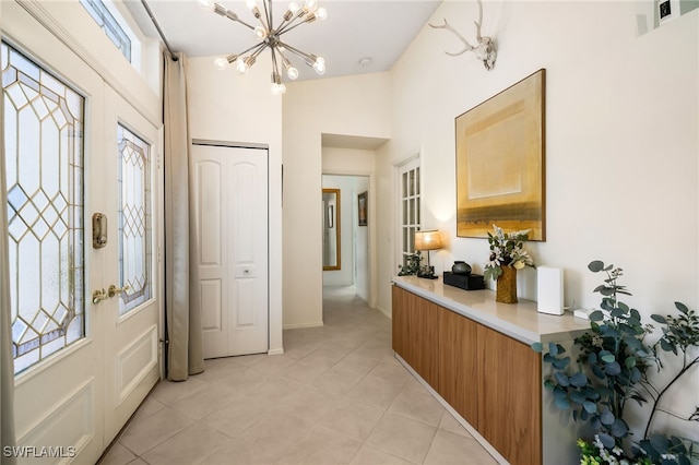 tiled foyer entrance featuring a wealth of natural light, vaulted ceiling, and an inviting chandelier