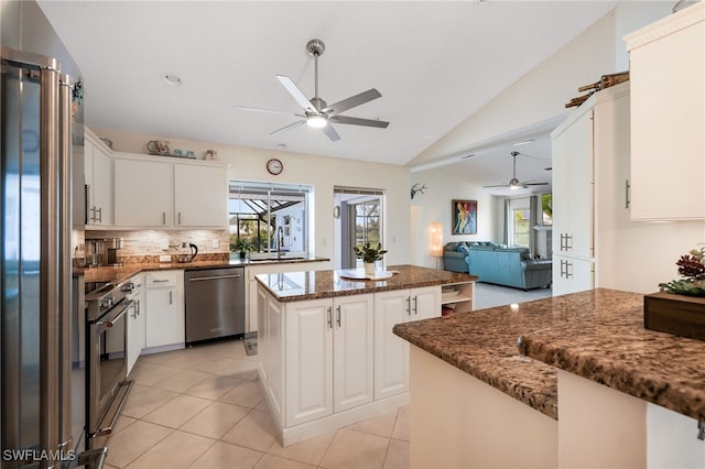 kitchen with a center island, appliances with stainless steel finishes, white cabinets, and vaulted ceiling