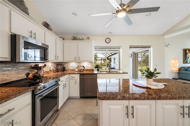 kitchen with lofted ceiling, white cabinets, and stainless steel appliances