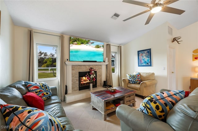 living room featuring lofted ceiling, light tile patterned flooring, a tiled fireplace, and ceiling fan