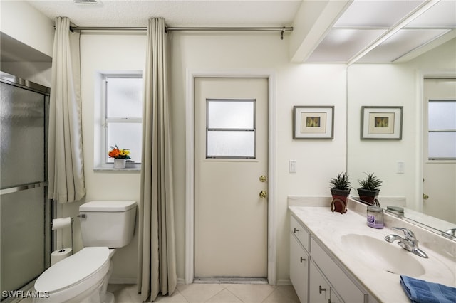 bathroom with vanity, a shower with shower door, toilet, and tile patterned floors