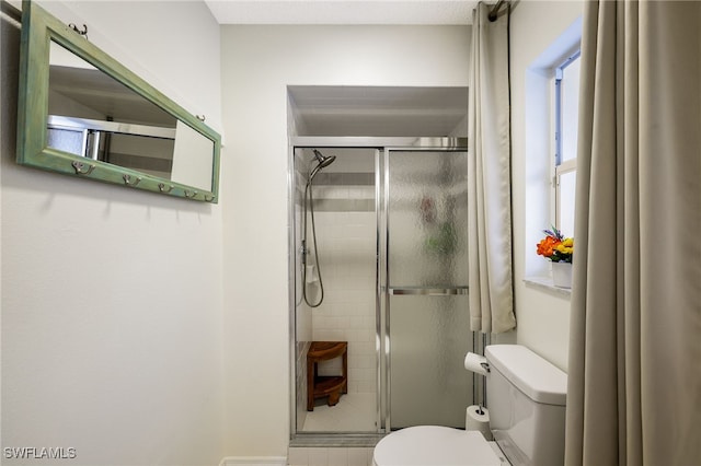 bathroom featuring a shower with door and toilet