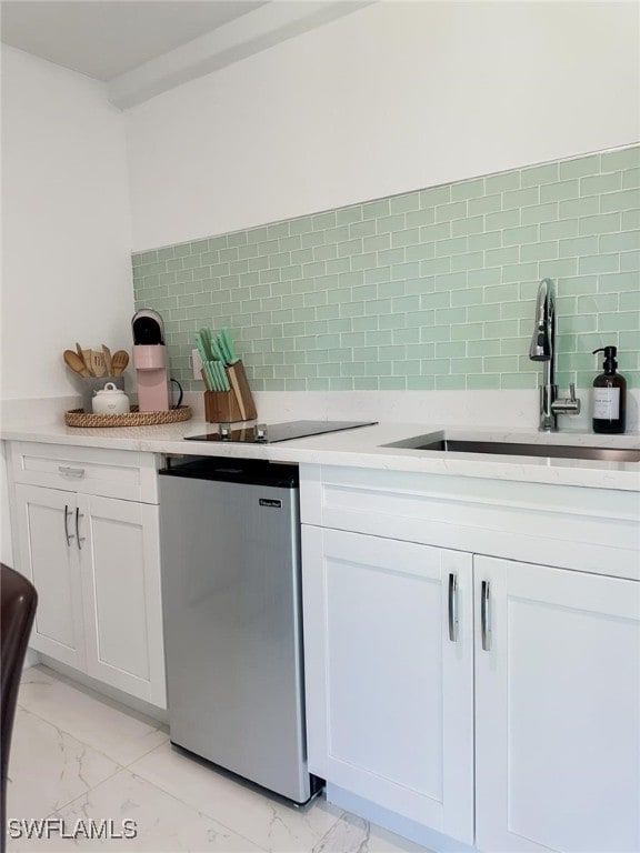 kitchen featuring stainless steel dishwasher, sink, white cabinets, and tasteful backsplash