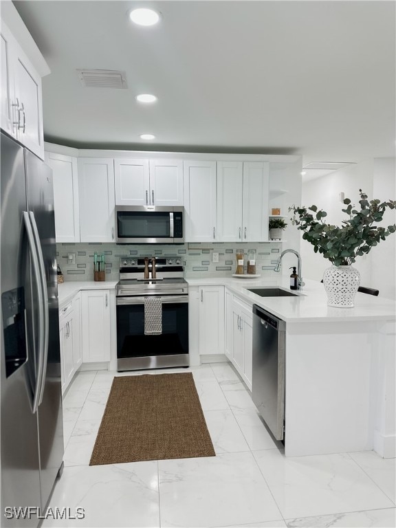 kitchen with sink, appliances with stainless steel finishes, backsplash, and white cabinets