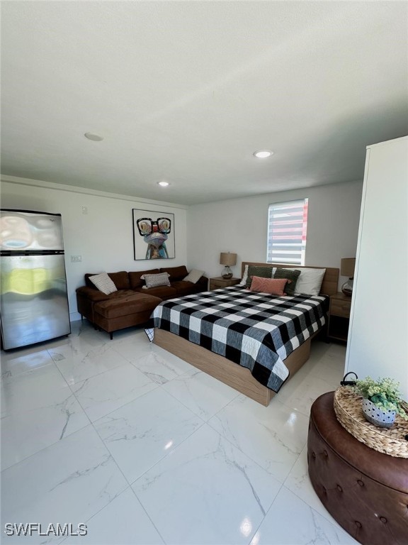 bedroom with crown molding and stainless steel refrigerator