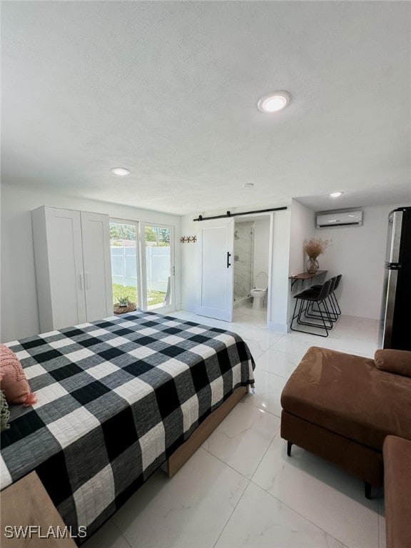 bedroom with a wall unit AC, a barn door, ensuite bath, and stainless steel refrigerator