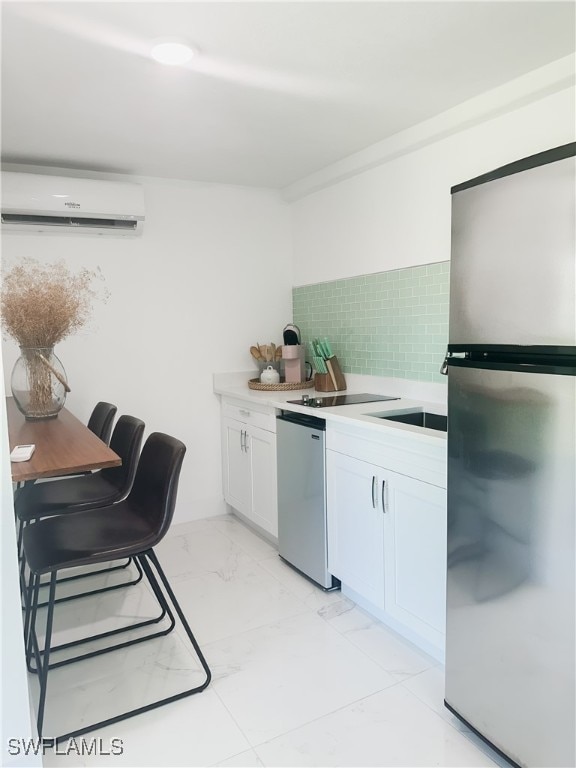 kitchen with appliances with stainless steel finishes, white cabinets, a wall mounted AC, and backsplash