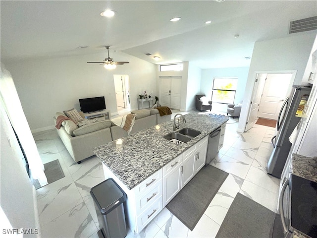 kitchen featuring appliances with stainless steel finishes, sink, an island with sink, white cabinetry, and vaulted ceiling