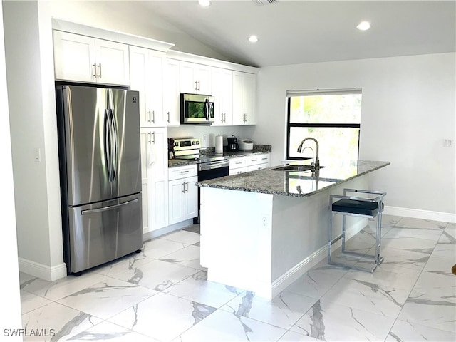 kitchen with lofted ceiling, stainless steel appliances, dark stone counters, sink, and white cabinets