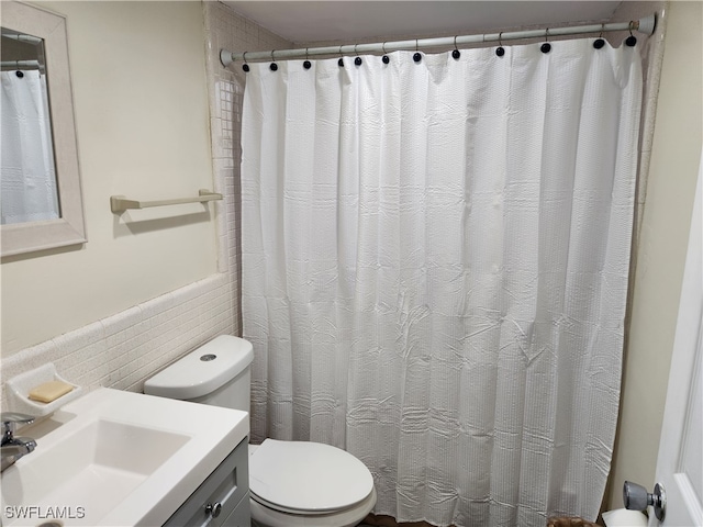 bathroom with vanity, tile walls, and toilet