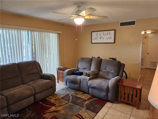 living room featuring a textured ceiling, ceiling fan, and light tile patterned flooring