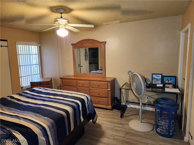 bedroom featuring ceiling fan, light hardwood / wood-style flooring, and a textured ceiling