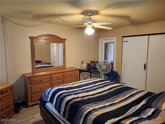 bedroom featuring ceiling fan, a closet, light hardwood / wood-style floors, and a textured ceiling