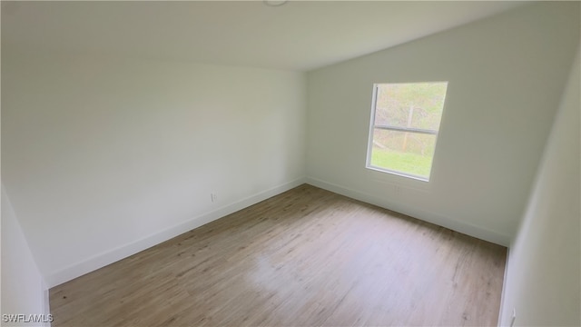 unfurnished room featuring light hardwood / wood-style flooring and vaulted ceiling