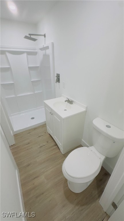 bathroom with vanity, toilet, hardwood / wood-style flooring, and a shower