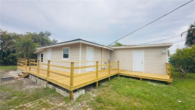 rear view of property featuring a wooden deck and a lawn