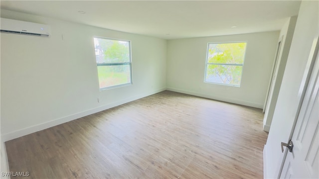 unfurnished room featuring a wall unit AC and light wood-type flooring