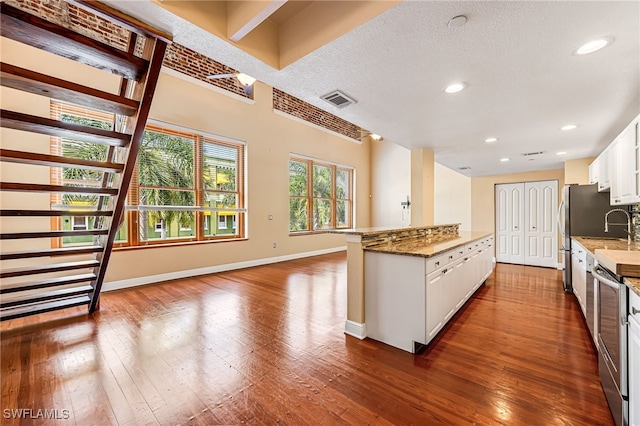 kitchen with stone countertops, a textured ceiling, dark hardwood / wood-style flooring, and white cabinets