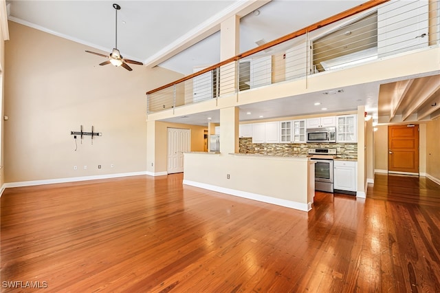 unfurnished living room with hardwood / wood-style floors, a high ceiling, and beam ceiling