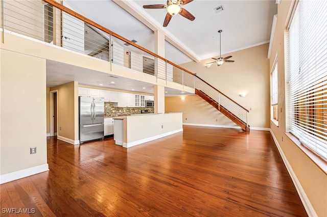 unfurnished living room with ornamental molding, ceiling fan, a high ceiling, and dark hardwood / wood-style flooring