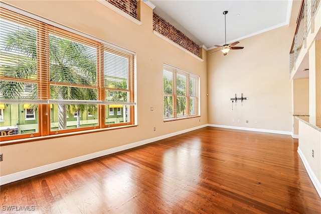 spare room featuring ornamental molding, a high ceiling, hardwood / wood-style flooring, and ceiling fan