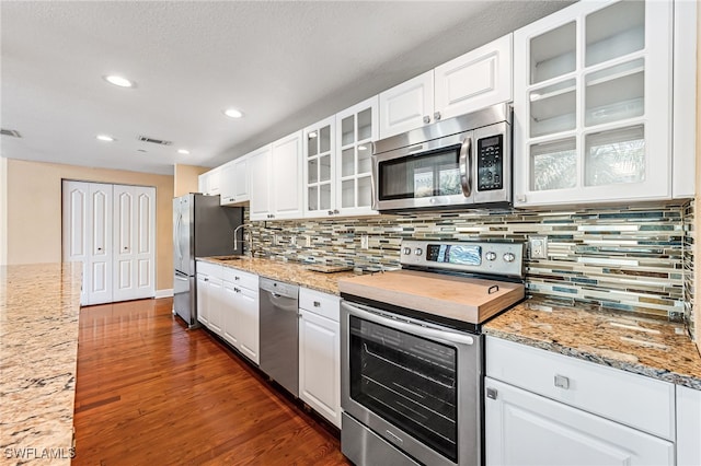 kitchen featuring appliances with stainless steel finishes, light stone counters, dark hardwood / wood-style floors, and white cabinets