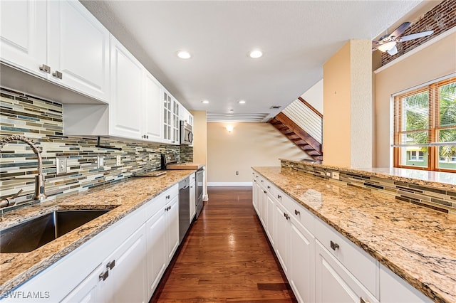 kitchen featuring appliances with stainless steel finishes, sink, white cabinets, light stone counters, and dark hardwood / wood-style floors