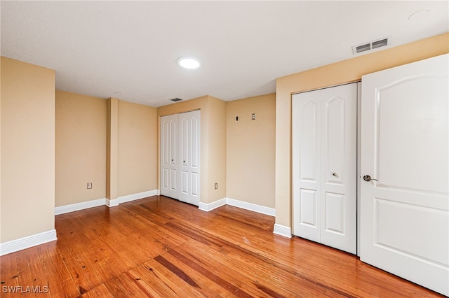 unfurnished bedroom featuring light hardwood / wood-style floors and multiple closets