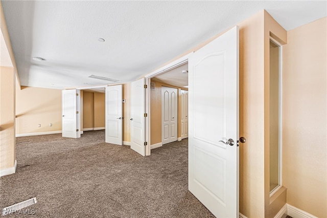 hallway featuring dark carpet and a textured ceiling