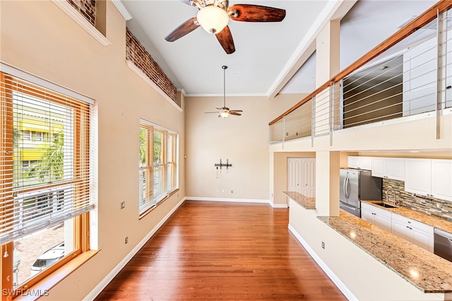 unfurnished living room with ornamental molding, ceiling fan, sink, and dark hardwood / wood-style flooring