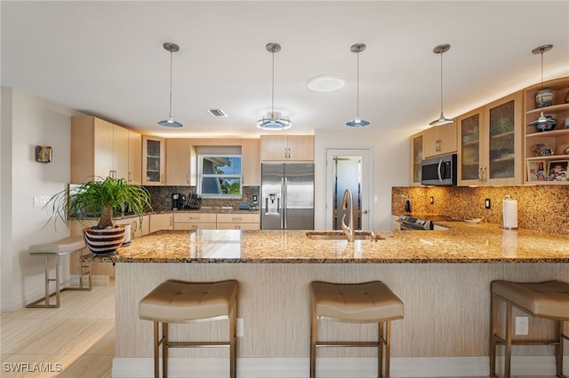 kitchen featuring backsplash, sink, hanging light fixtures, kitchen peninsula, and stainless steel appliances