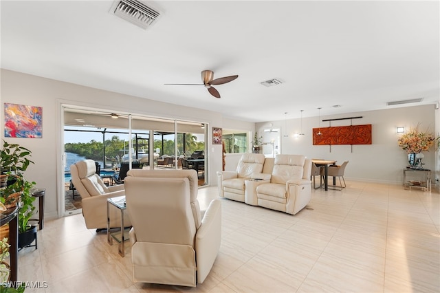 living area featuring light tile patterned floors, ceiling fan, visible vents, and baseboards