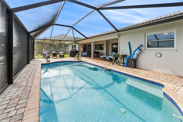 outdoor pool featuring glass enclosure and a patio