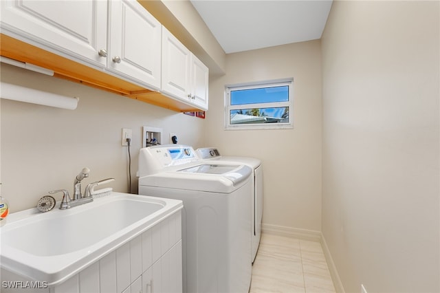 laundry area featuring washer and clothes dryer, cabinets, light tile patterned floors, and sink