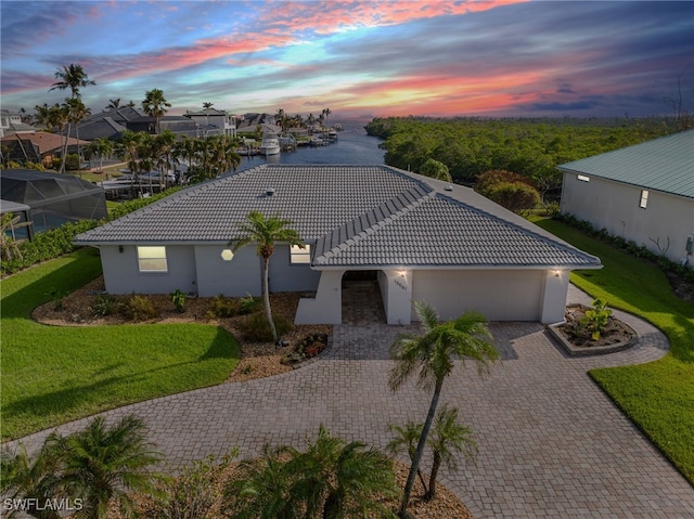 view of front of home featuring a lawn, a water view, and a garage