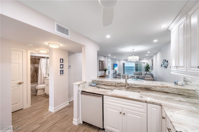 kitchen with light stone countertops, dishwasher, white cabinets, and light wood-type flooring