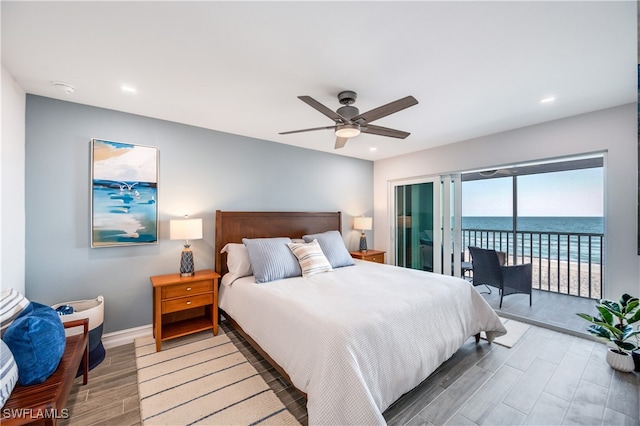 bedroom featuring access to outside, ceiling fan, hardwood / wood-style floors, and a water view