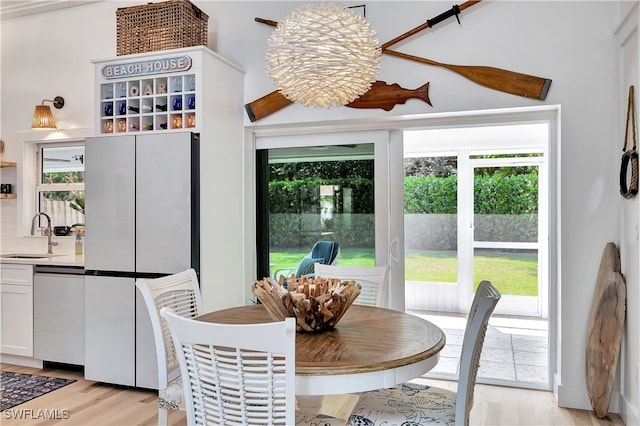 dining room with sink, a notable chandelier, light wood-type flooring, and plenty of natural light