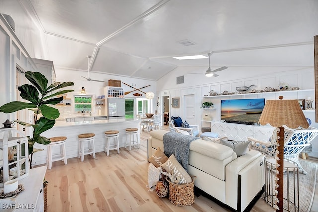 living room featuring ceiling fan, lofted ceiling, and light wood-type flooring