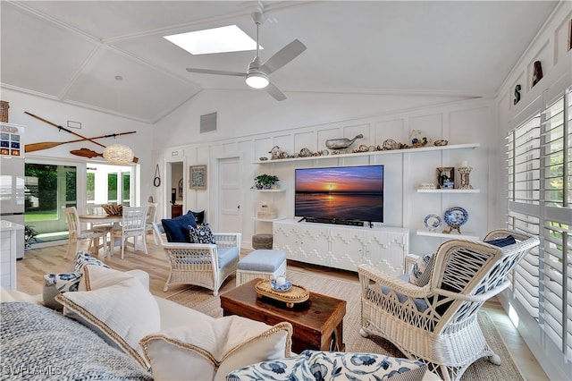 living room with a skylight, high vaulted ceiling, light wood-type flooring, and ceiling fan